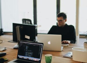 A web developer working on code in a modern office setting with multiple devices.